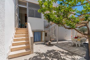 A staircase leading to a balcony with a view of a building, a table with chairs, and a tree. - 3057 Villa Perla Marina- Appartamento PP by Barbarhouse (Torricella)