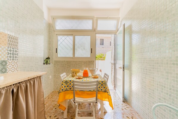 A small kitchen with a table set for two, a window, and a view of the outside. - 3057 Villa Perla Marina- Appartamento PP by Barbarhouse (Torricella)