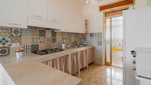 A kitchen with patterned tiles, white cabinets, a gas stove, and a refrigerator.