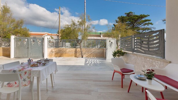 An outdoor patio with a table set for dining, white chairs, and a sofa. - 2126 Villa Ippocampo - Appartamento Blu by Barbarhouse (Manduria)