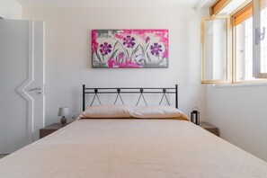A bedroom with a bed, a nightstand, a lamp, and a painting on the wall.