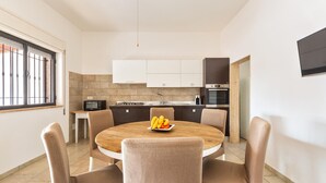 Eine moderne Küche mit weißen Schränken, einem Holztisch und einer Obstschale.