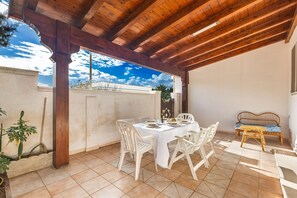 An outdoor patio with a wooden pergola, a white table set for dining, and a wicker sofa. - 2680 Villetta Filomena - Appartamento Filo by Barbarhouse (Manduria)