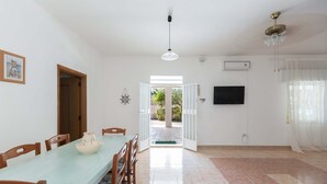 A dining area with a table and chairs, a ceiling fan, and a television on the wall. - 3041 Villetta Sunshine by Barbarhouse (Manduria)