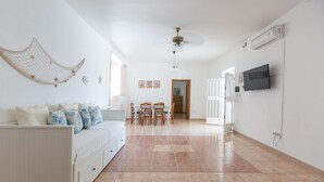 A spacious living area with a white sofa, a dining table with chairs, a ceiling fan, and a mounted TV. - 3041 Villetta Sunshine by Barbarhouse (Manduria)