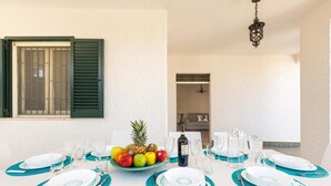 Une table à manger dressée avec des assiettes, des couverts et un panier de fruits.