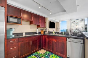 A modern kitchen with dark wood cabinets, a microwave, and a dishwasher. - 8th Floor Gold Coast 1 Bedroom with Great Views, Kitchen & Den (Honolulu)