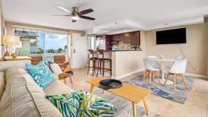 A modern living room with a sofa, coffee table, and a dining area with chairs and a table.