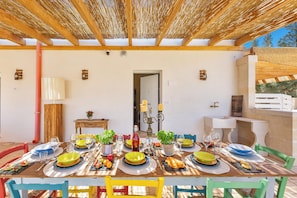 Un coin repas avec une table en bois dressée pour le repas, entourée de chaises aux couleurs vives.