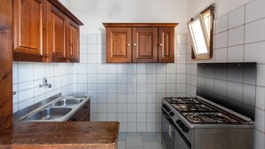 A kitchen with wooden cabinets, a stainless steel sink, and a gas stove. - 2686 Villetta Fiore di Maggio by Barbarhouse (Porto Cesareo)