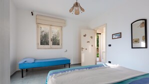 A bedroom with a bed, a blue bench, a window, a door, and a mirror. - 2686 Villetta Fiore di Maggio by Barbarhouse (Porto Cesareo)
