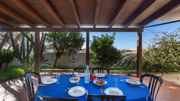 A covered outdoor dining area with a blue tablecloth, set for four people. - 2686 Villetta Fiore di Maggio by Barbarhouse (Porto Cesareo)