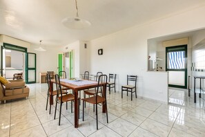 A spacious dining area with a wooden table and chairs, a sofa, and a green door leading to another room.