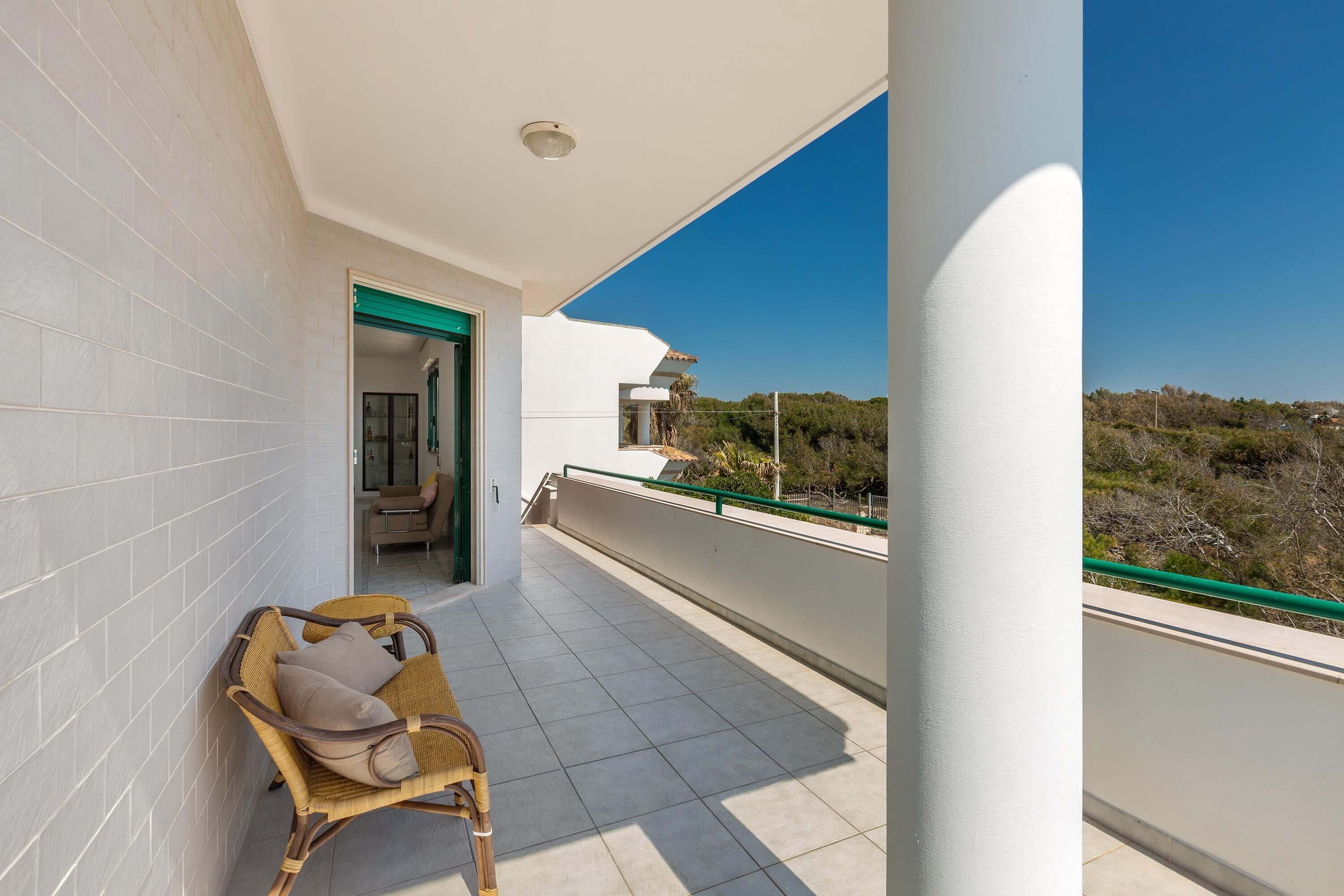 Un balcon avec un fauteuil en osier et une vue sur le paysage.
