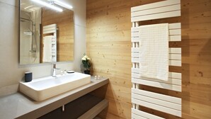 A modern bathroom with a wooden wall, a white sink, and a towel rack. - Bain À Remous Privé! Chalet au coeur du Village (L'Alpe d'Huez)