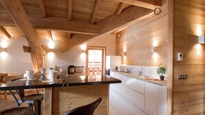 A modern kitchen with wooden beams, a central island, and built-in appliances. - Bain À Remous Privé! Chalet au coeur du Village (L'Alpe d'Huez)