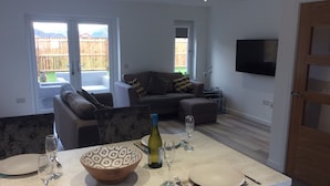 Een moderne woonkamer met een bank, een salontafel en een aan de muur bevestigde televisie.