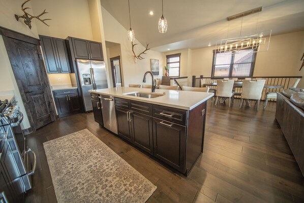 A modern kitchen with dark cabinetry, a large island, stainless steel appliances, and a rustic antler decoration.