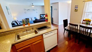 A modern kitchen with granite countertops, a dishwasher, and a dining area with a table and chairs. - ENTIRE Place 2 Bed 2 Bath. Everything You Need for a Hassle-Free Stay in Biloxi. (Biloxi)