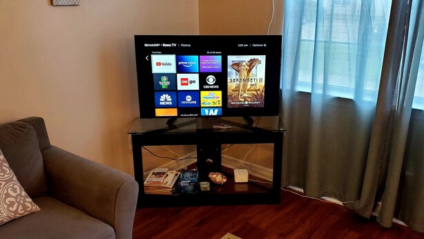 A television on a black stand with a remote control, displaying a Roku TV interface. - ENTIRE Place 2 Bed 2 Bath. Everything You Need for a Hassle-Free Stay in Biloxi. (Biloxi)
