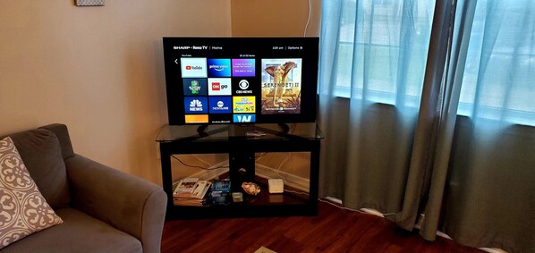 A television on a black stand with a remote control, displaying a Roku TV interface.