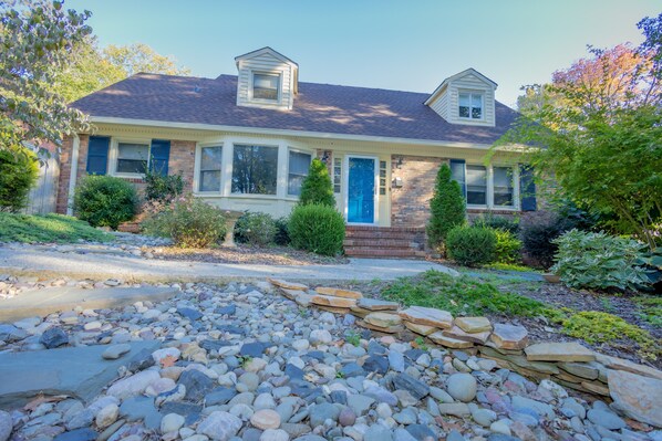 A two-story house with a blue front door, a small front porch, and a stone pathway leading to the entrance.