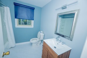 A bathroom with a toilet, sink, and mirror.
