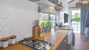A kitchen with a gas stove, wooden countertop, and decorative items. - New Tiny House (Camp Hill)
