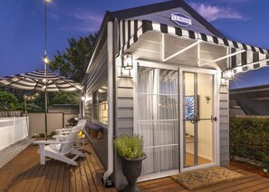 A small, single-story building with a covered patio area, a grill, and outdoor seating.