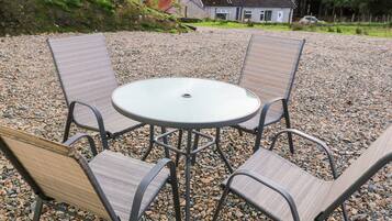 A round table with four chairs in a gravel area.
