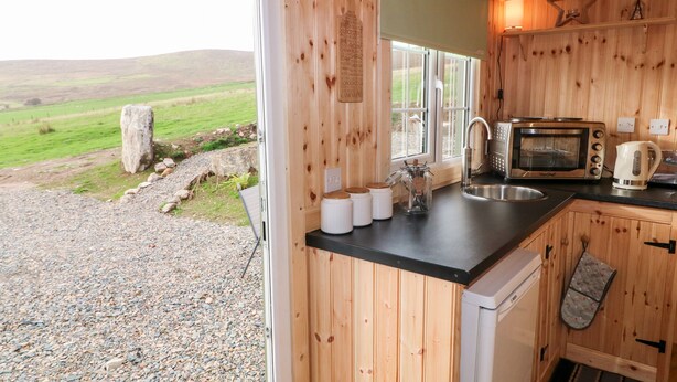 A wooden cabin kitchen with a view of a grassy field.