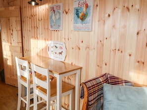 A wooden interior with a wooden table and chairs, a poster of farm fresh eggs, and a placemat with farm animals. - Shepherds Retreat Glenlark (Omagh)