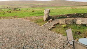 A gravel patio with a stone structure and a metal chair.