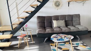 A modern living room with a grey sofa, a coffee table with magazines, a small side table with a flower, and a staircase with wooden steps. - Small sugar bowl duplex with sea view (Cul de Sac)