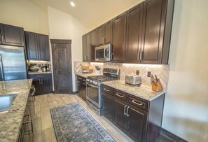 A modern kitchen with dark wood cabinets, stainless steel appliances, and a granite countertop.