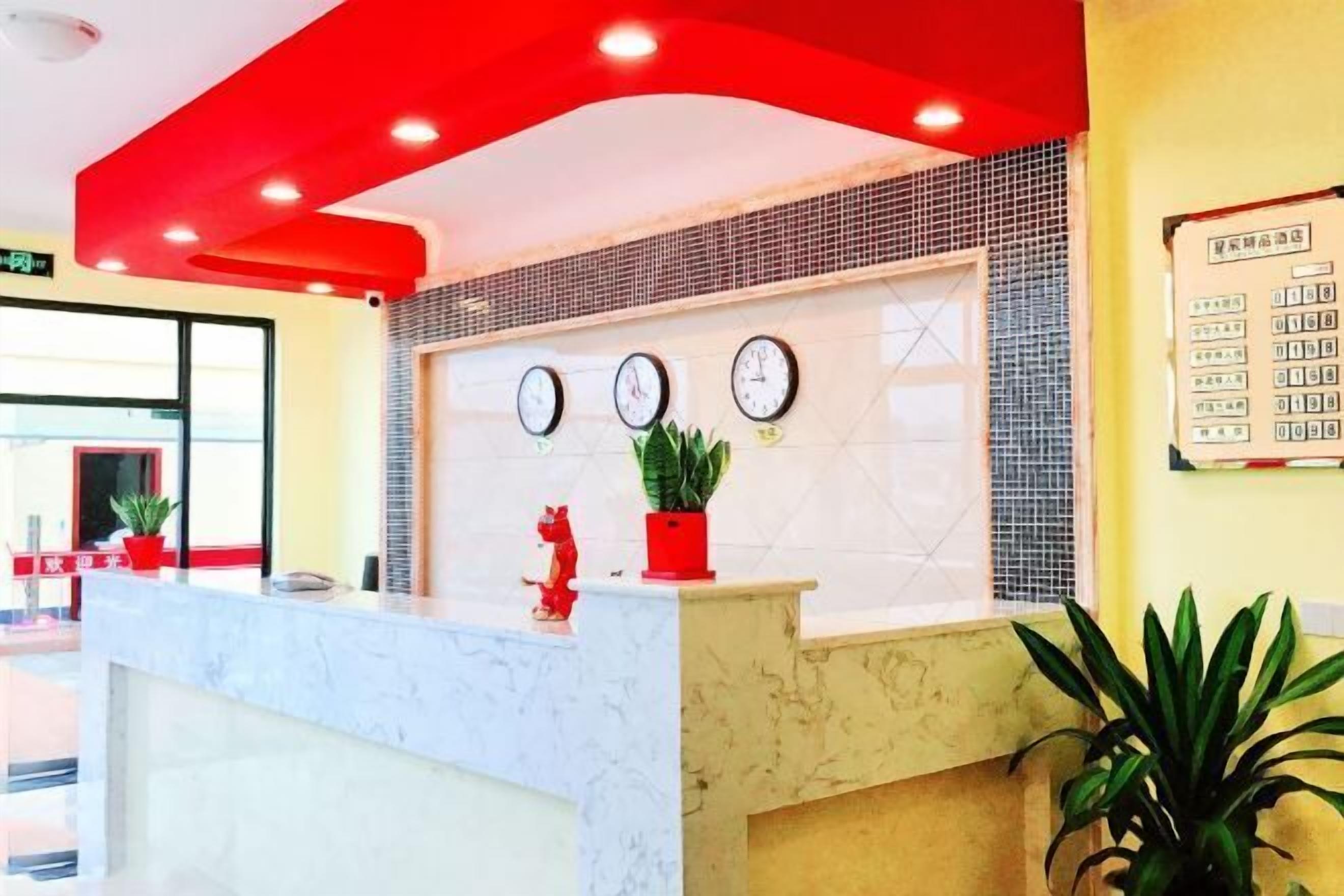 Un mostrador de recepción con encimera de mármol, tres relojes de pared y un adorno rojo sobre el mostrador.