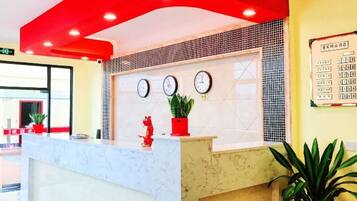 Un mostrador de recepción con encimera de mármol, tres relojes de pared y un adorno rojo sobre el mostrador.