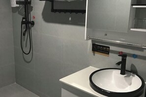 Un baño con un lavamanos blanco, grifo negro y ducha.