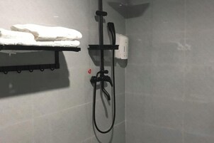A shower area with a towel rack and a handheld showerhead.