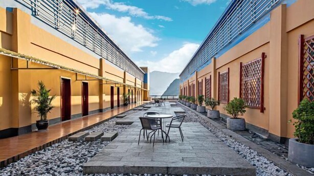 A corridor with a stone floor, potted plants, and a seating area with chairs. - Duyun Star Boutique Hotel (Weinan Vocational and Technical College) (Duyun)