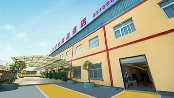 A hotel with a yellow facade, a covered entrance, and a clear sky.
