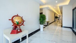 A hotel lobby with a polished marble floor, a globe on a white table, and a potted plant. - Duyun Star Boutique Hotel (Weinan Vocational and Technical College) (Duyun)