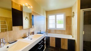 Un baño con dos lavamanos, un espejo grande y una ventana.