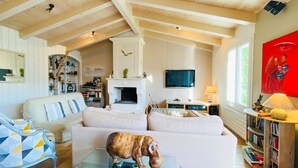 A cozy living room with a fireplace, a sofa, a coffee table, and a bookshelf. - Pretty villa close to beaches and cycle paths (LA COUARDE SUR MER)
