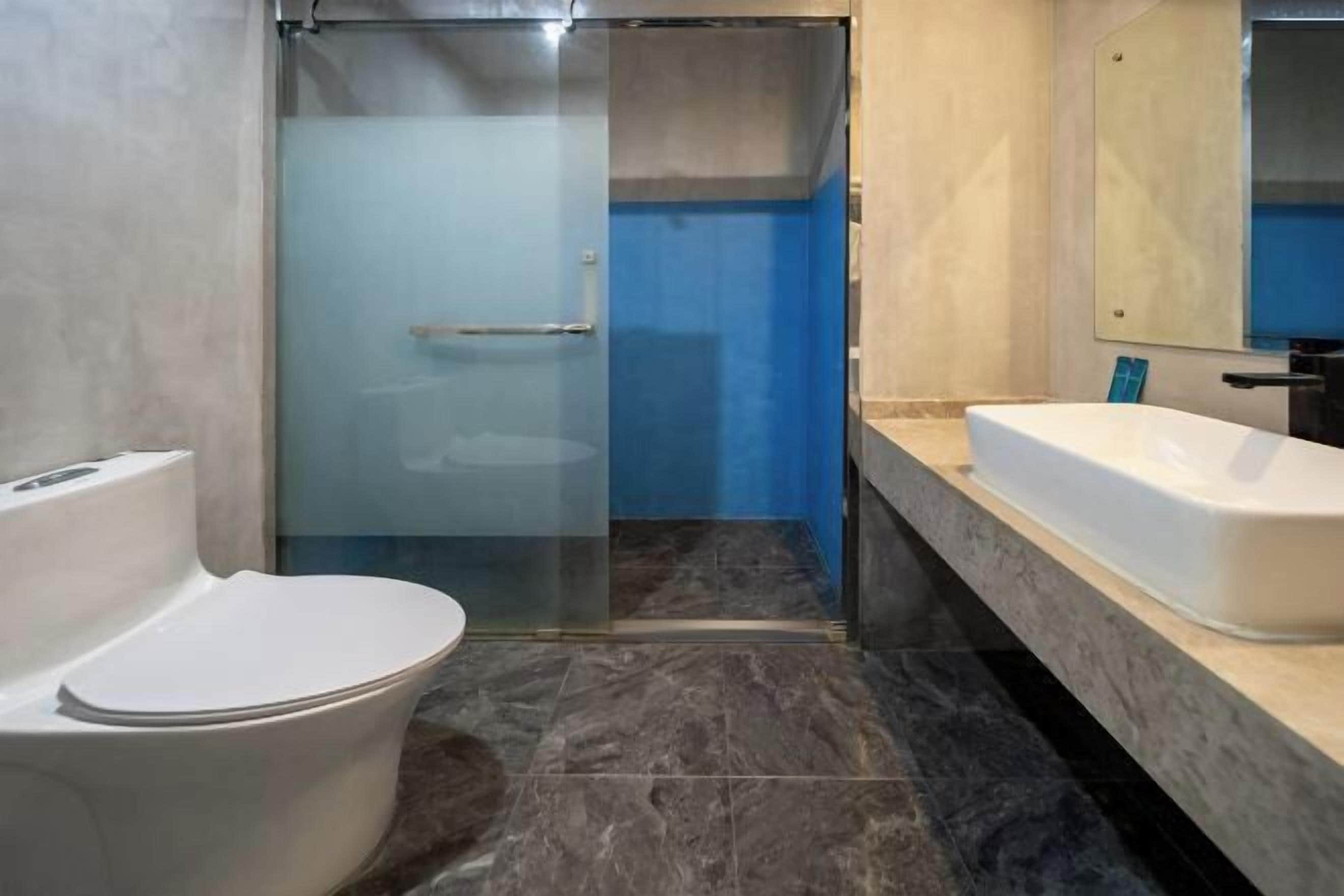 Een moderne badkamer met een douchecabine van glas, een wit toilet en een groot bad.