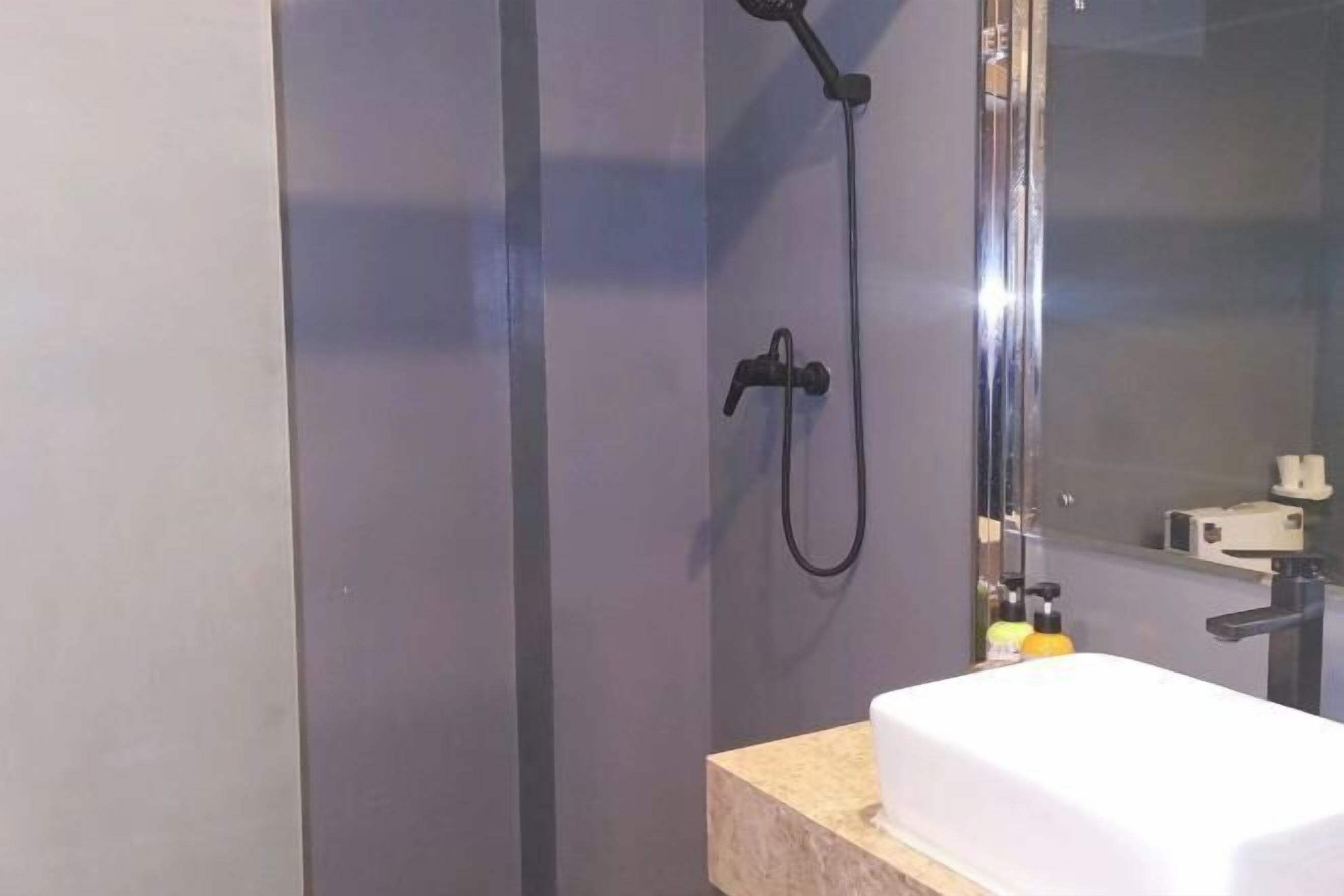 A modern bathroom with a glass shower enclosure, a white sink, and a mirror.