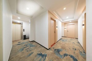A hotel corridor with carpeted flooring, doors, and a ceiling with recessed lighting. - Huahuitong Hotel (Wujiang Shaoguan Station) (Shaoguan)