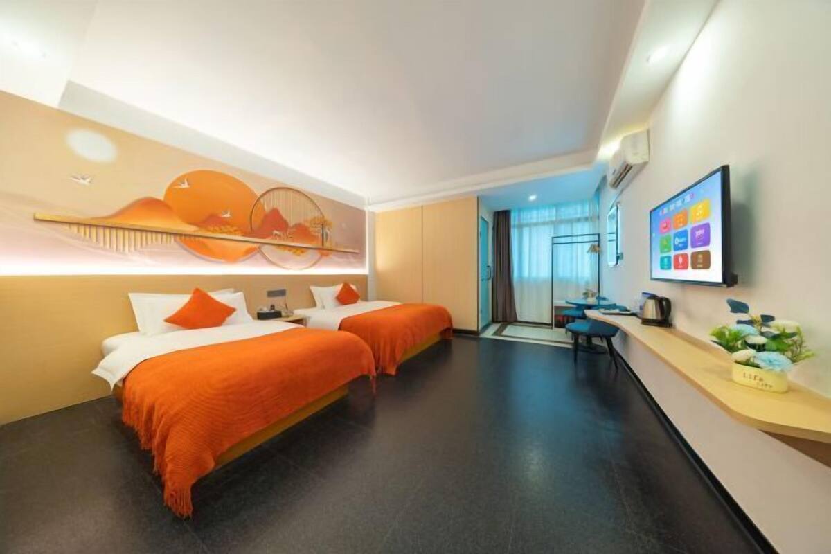 Een hotelkamer met twee bedden, een bureau, een televisie en een decoratief wandobject.