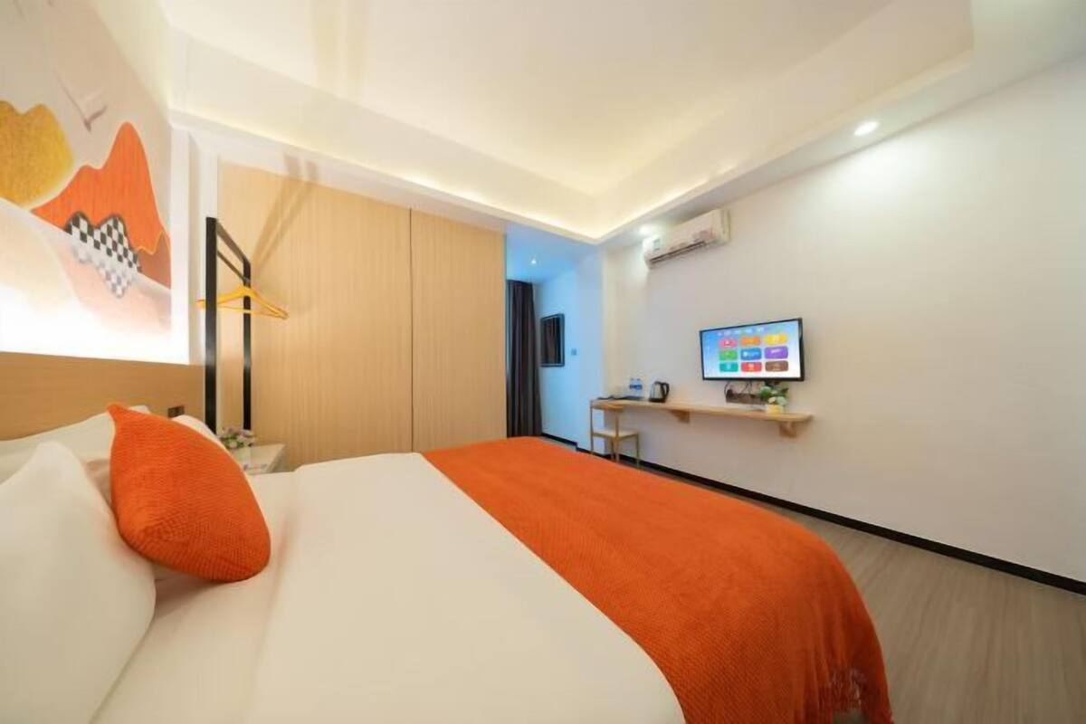 Een hotelkamer met een bed, een televisie, een bureau en een kledingkast.
