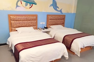 Habitación de hotel con dos camas, cada una con cabecero de madera y ropa de cama blanca. Hay murales en las paredes con delfines y una escena de playa.
